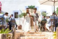 Can Frare wedding ibiza couple just married holding hands, walking down stone steps with guests sitting either side