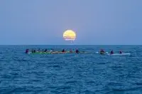 sunset Ibiza kayaks with a round sun setting in the sky against blue sky over the sea