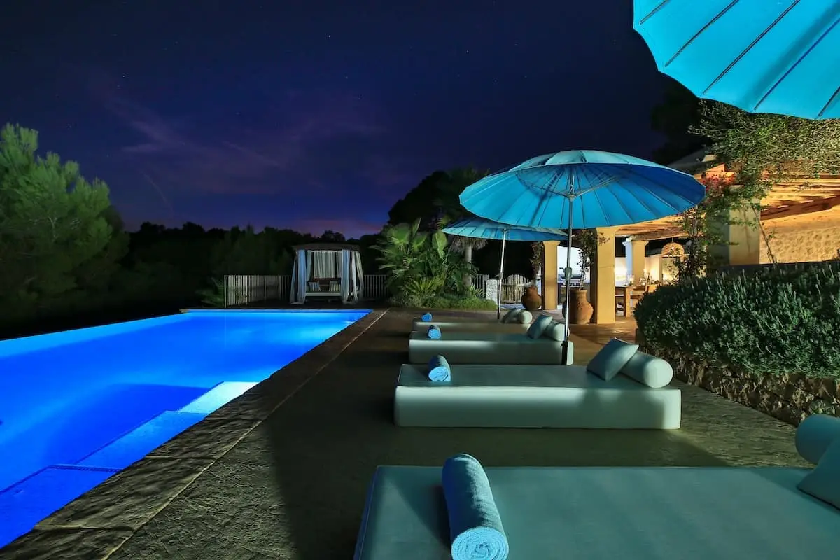 blue pool at night with parasols open