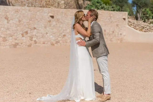 Can Frare ibiza wedding couple kissing in front of stone wall