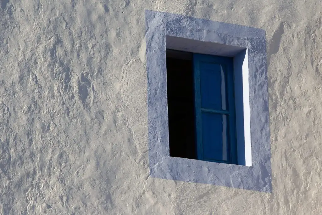 old finca style window with pale blue painted surround against white washed walls