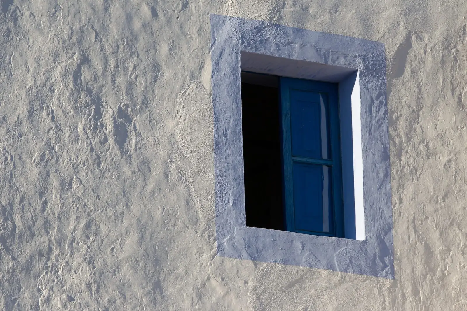 old finca style window with pale blue painted surround against white washed walls