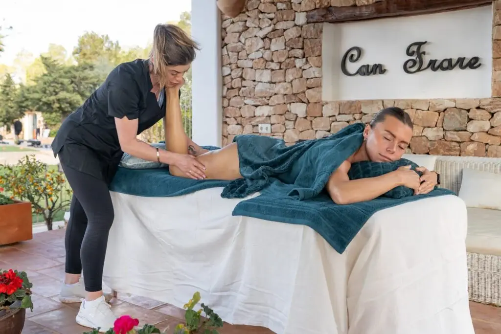 on-site massage therapy Ibiza, female massage therapist massaging a female with the can frare ibiza signage in the background