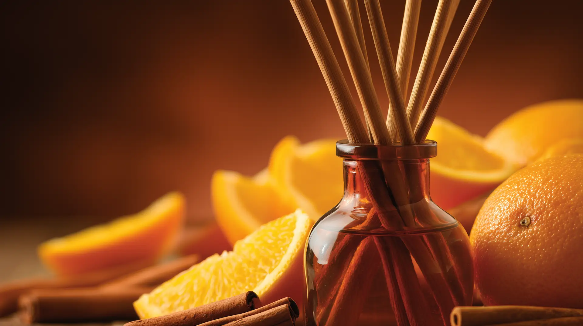 scent of can frare ibiza glass diffuser with scented sticks and oranges in the background